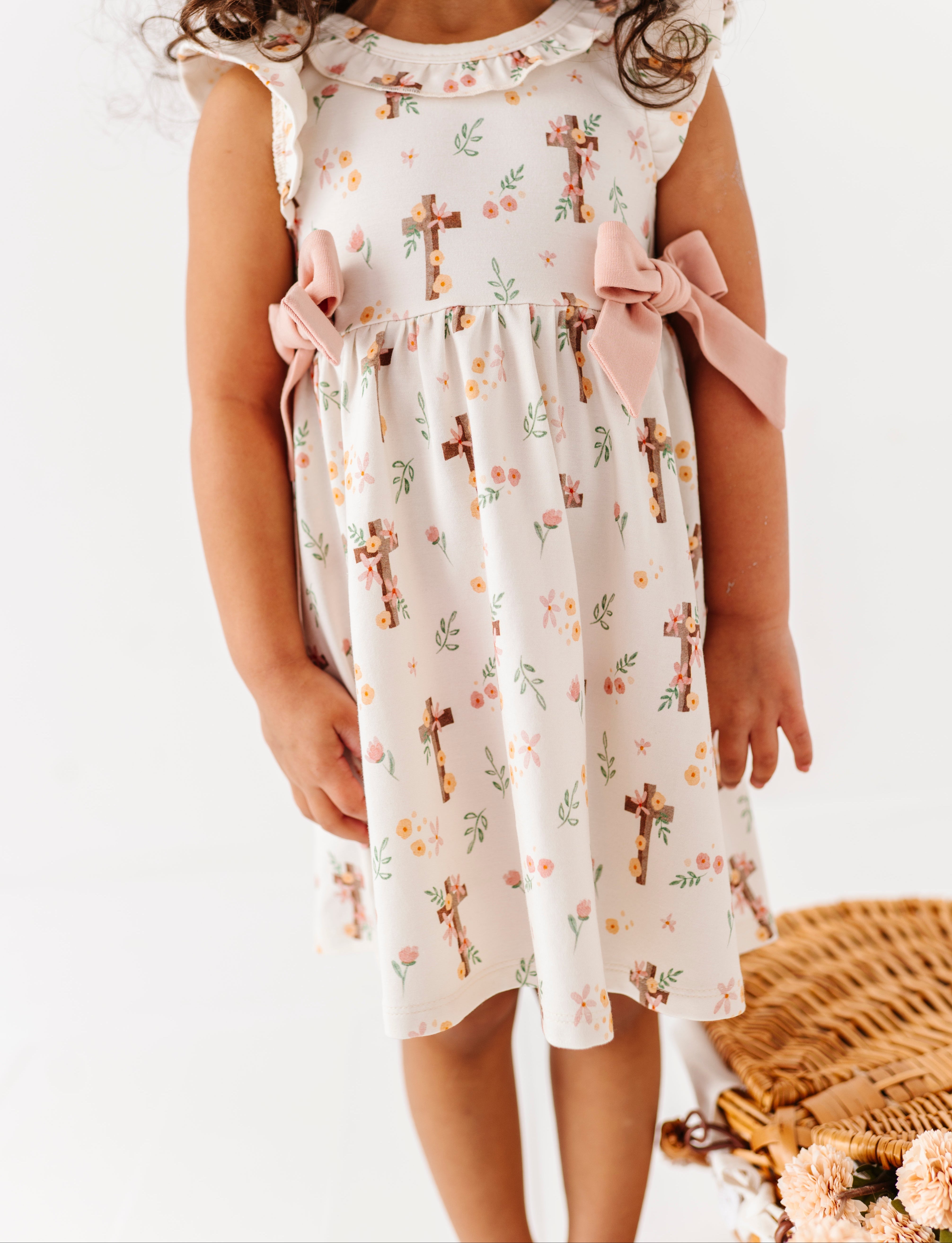 Young girl wearing a floral bamboo dress with cross patterns on a white background
